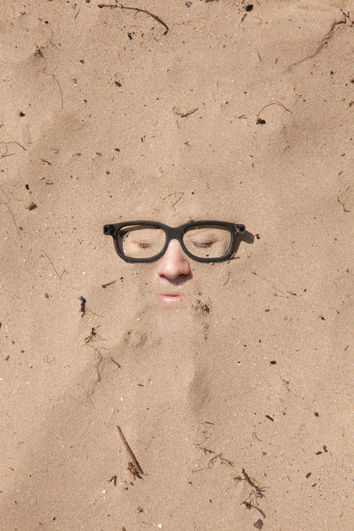 a mans face appearing in the sand