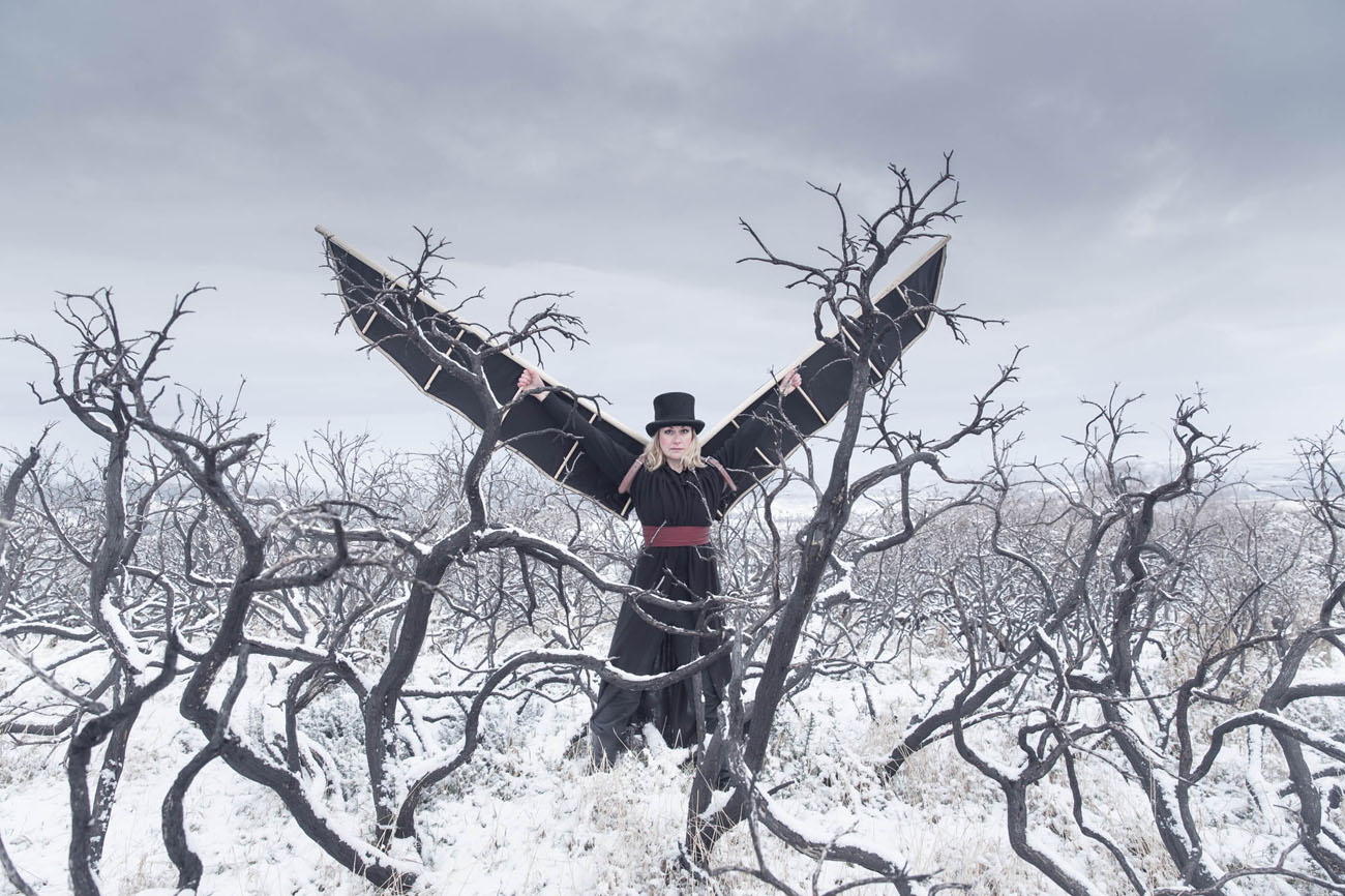 witch with top hat and wings in a burned out snowy winter landscape
