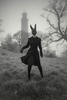 a woman with a hare mask on Calton hill with a tower in the background
