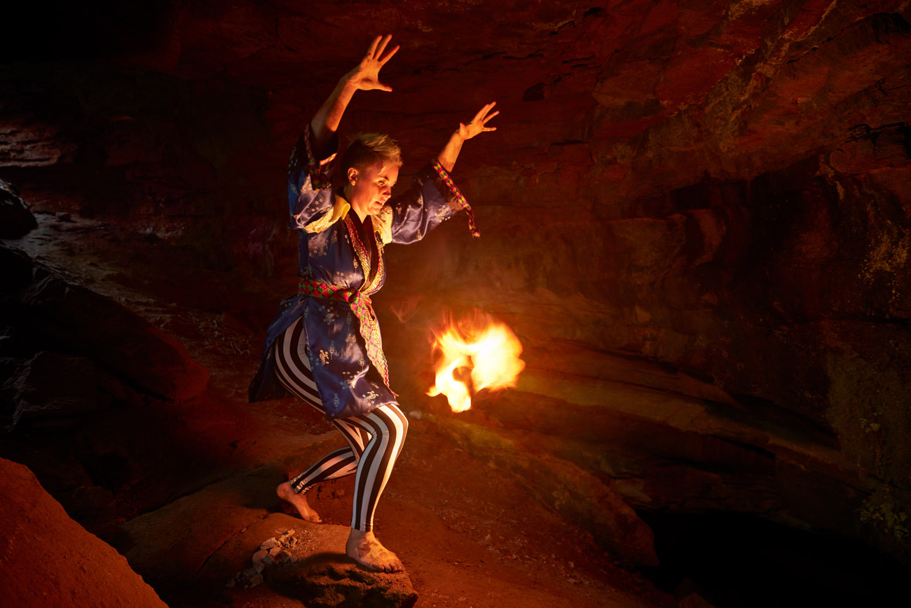 artist Kirsty Whiten in a cave in Blebo woods appearing as Tatwari, a god of fire.
