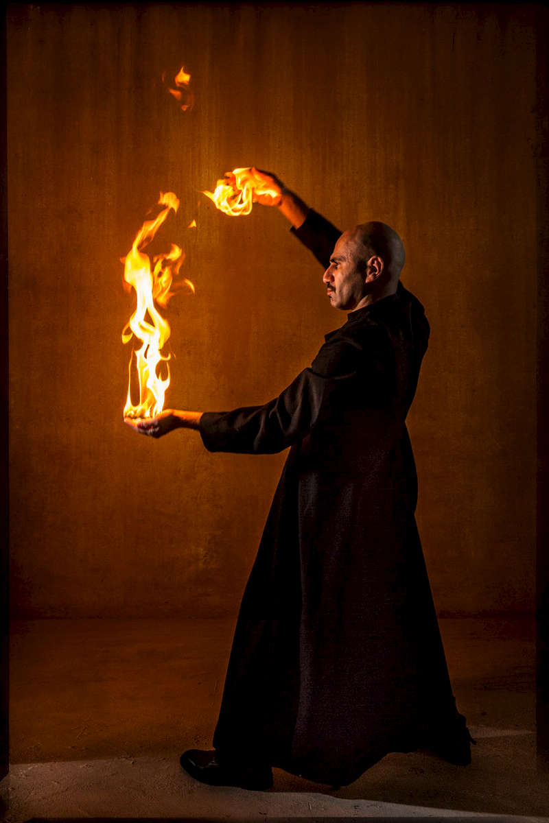 man indoors with his hands on fire.