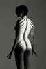 fine art black and white studio female nude of a woman roarie yum, with projected feathers  