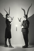 A couple standling in a studio holding Dorcus horns lit by a single  candle with horn shadows