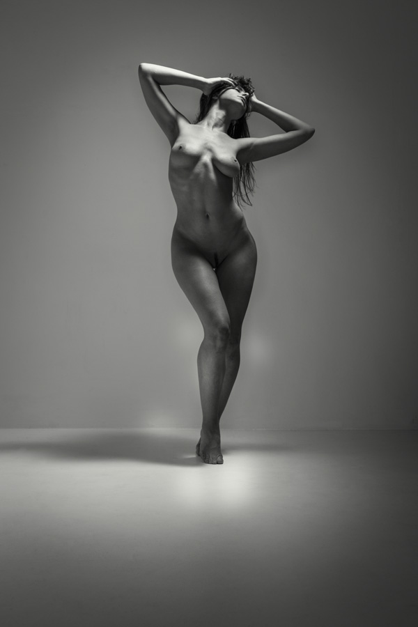 Nude photo of a beautiful shapely woman in a studio. Black and white fine art nude of a woman holding her head.