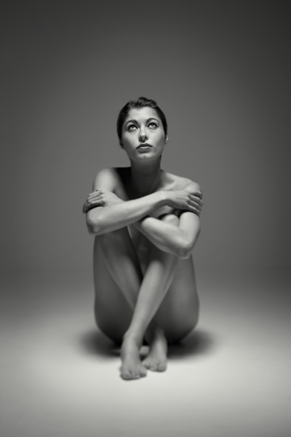 seated naked girl in a studio. Fine art b+w nude of a beautiful naked woman