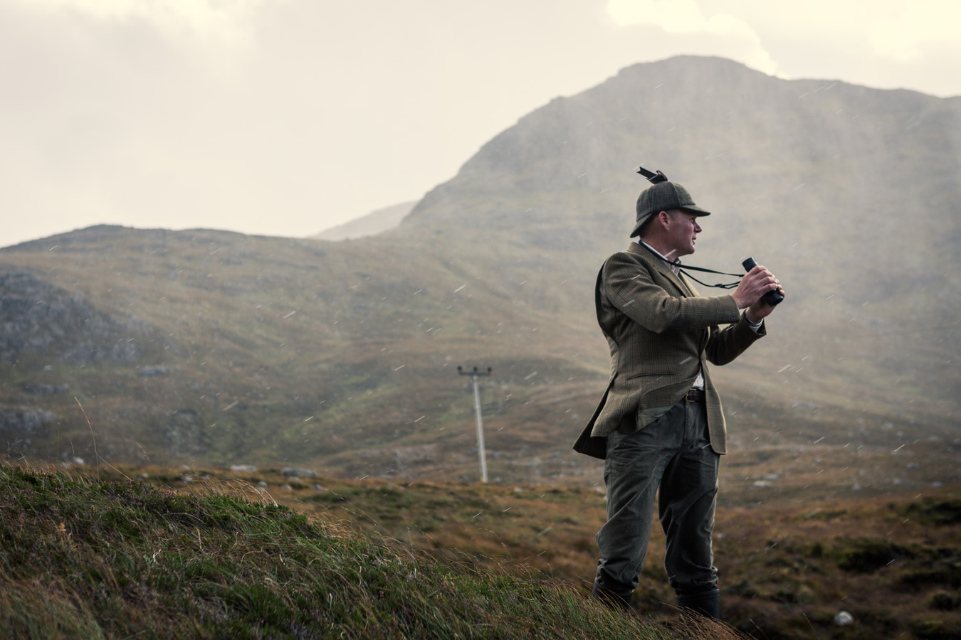Gamekeeper in a deerstalker out in the rain on the Clisham mountain