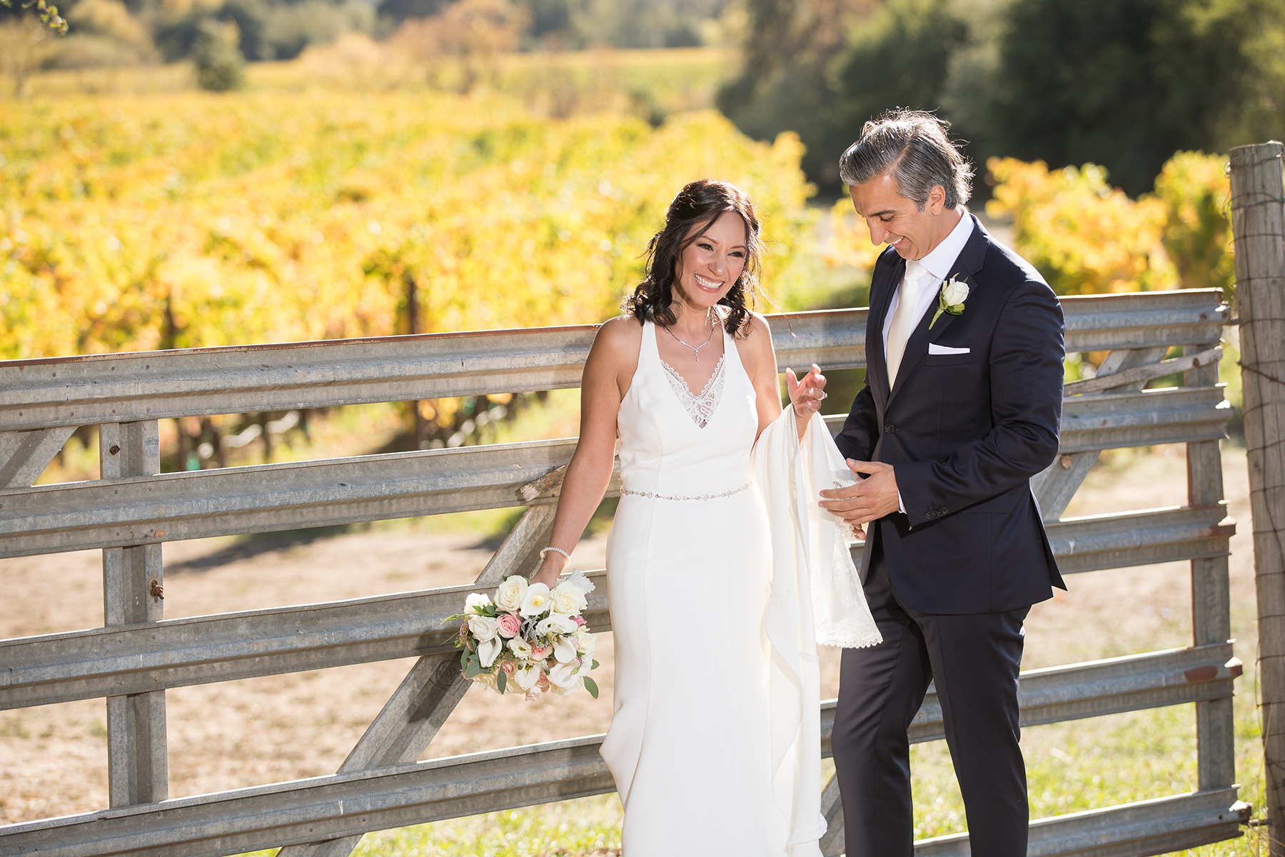 In the midst of the picturesque vineyards at Meritage Resort in Napa Valley, the bride and groom come together to share a heartfelt and romantic moment. The couple stands surrounded by thriving grapevines adorned with ripe fruit, representing a sense of abundance and the journey of growth. Against the backdrop of the resort's architectural beauty and the gentle slopes of rolling hills, this image perfectly encapsulates the beauty of their union set against the renowned wine country scenery of Napa