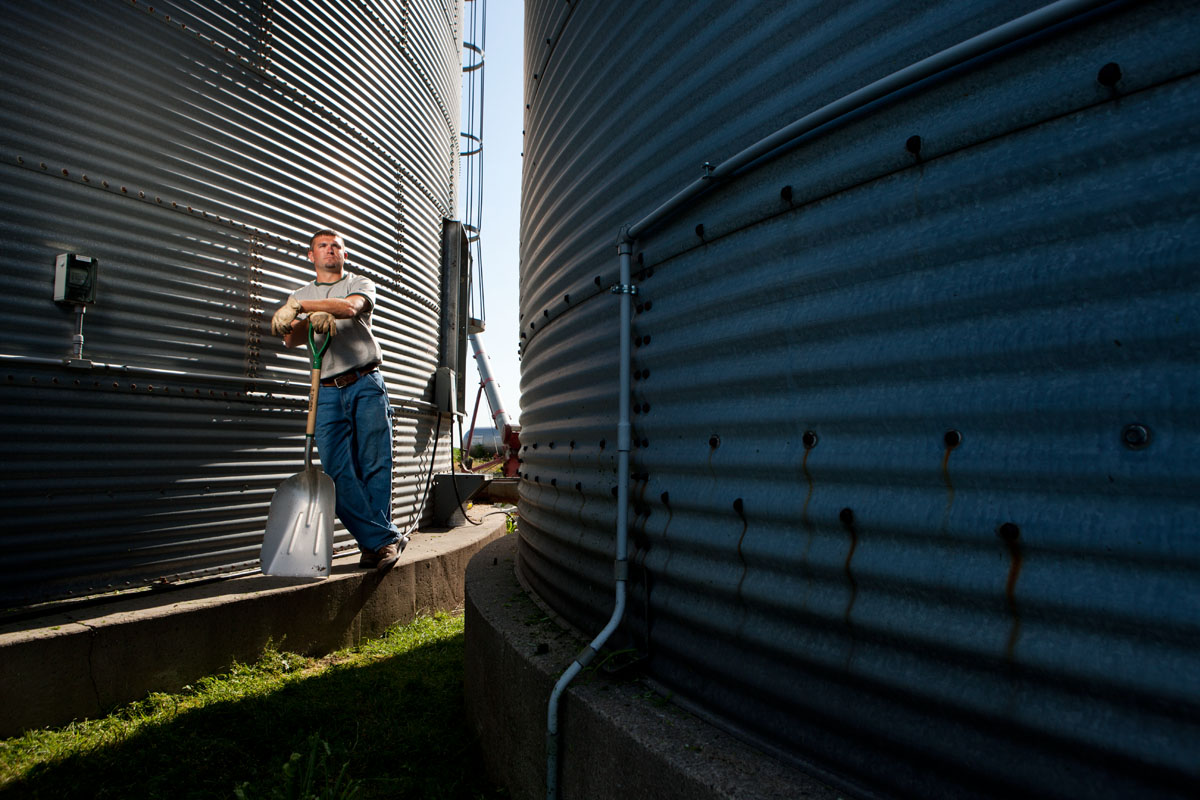 Working Farmer shot for Unity Seeds standing between two grain storage bins.
