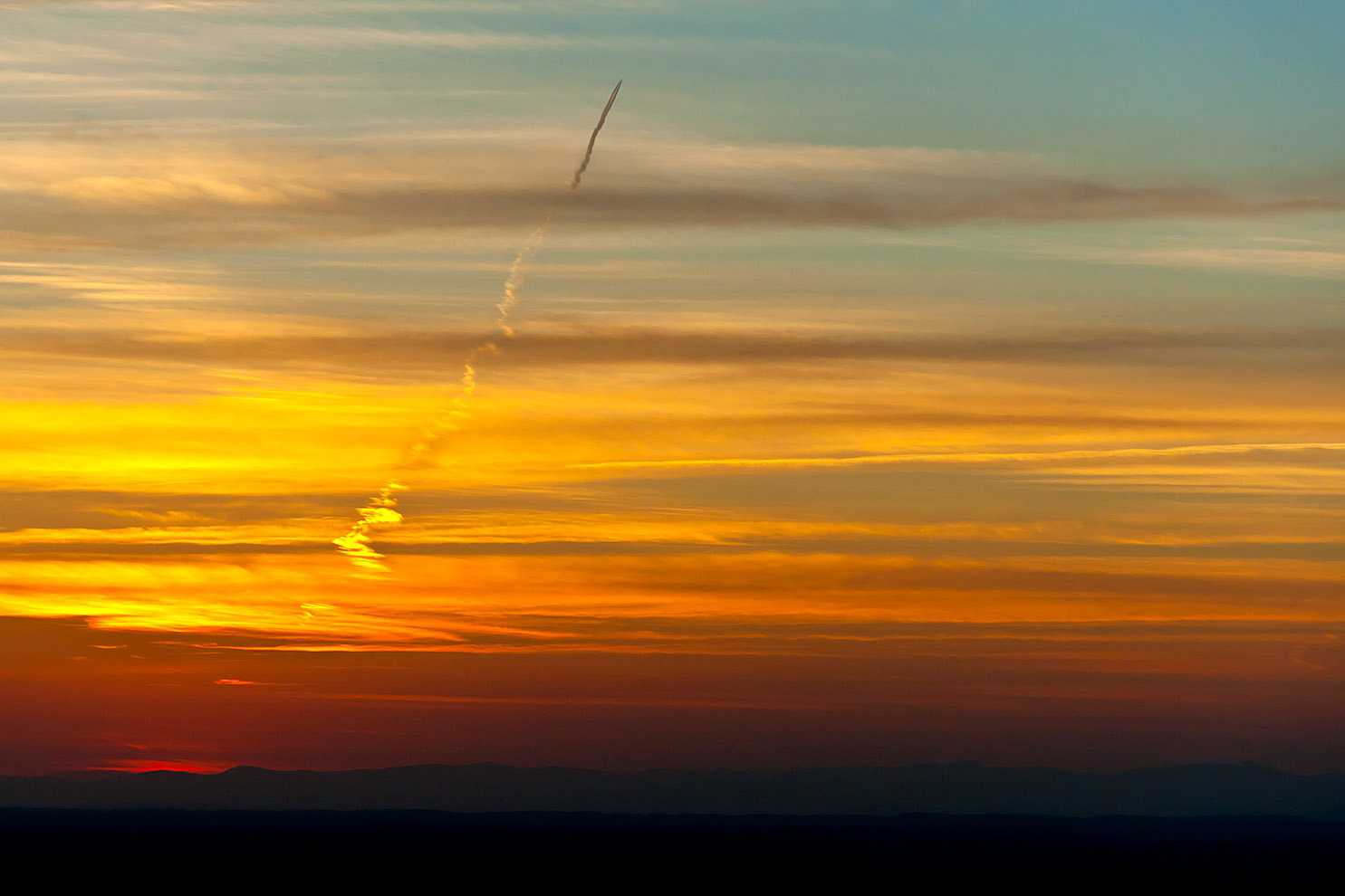jet trail through clouds at sunset