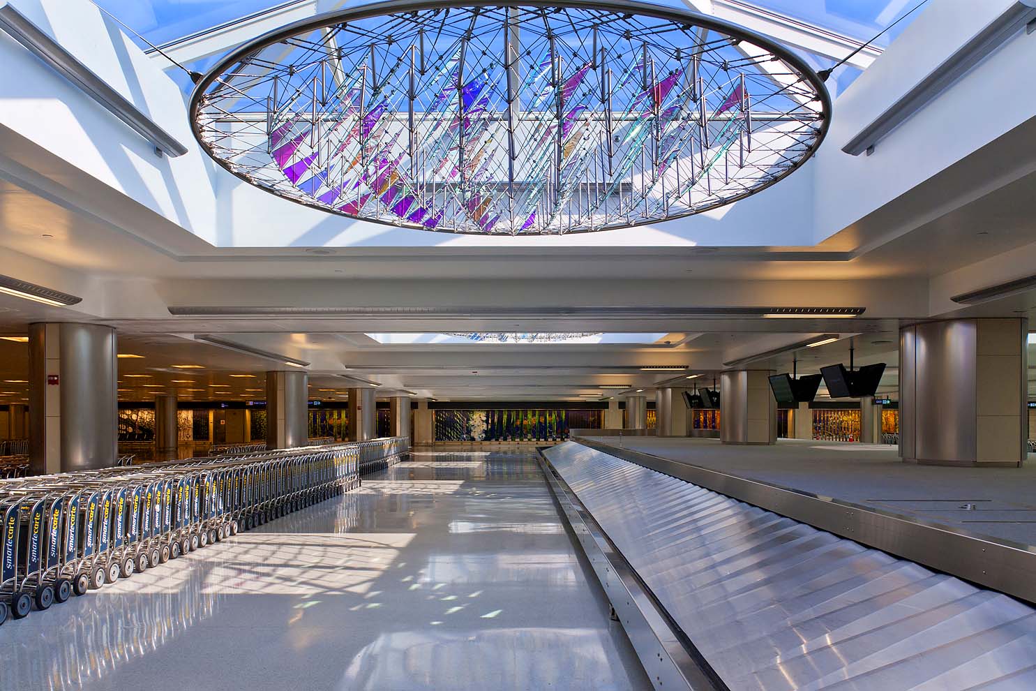 dichroic glass sculpture in skylight next to baggage carousel