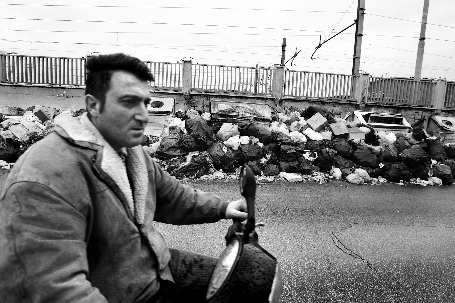 A man rides a motorcycle down a street full of garbage in Caserta, the outskirts of Naples, Italy, on February 21, 2008.