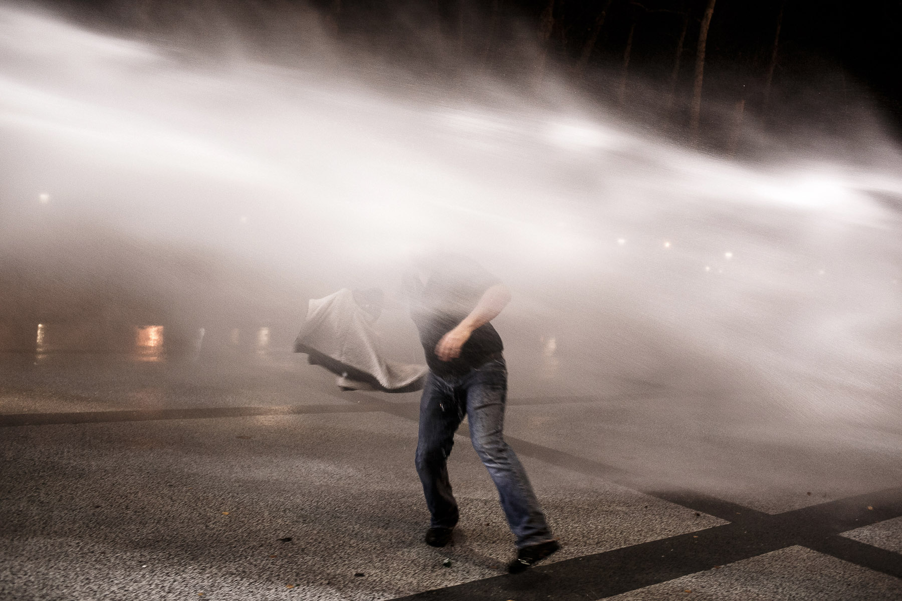 A protester tries to evade a water canon jet during anti-government protests in Ljubljana, Slovenia, on November 30, 2012. This was the first time in history of the country that the water canon was used.