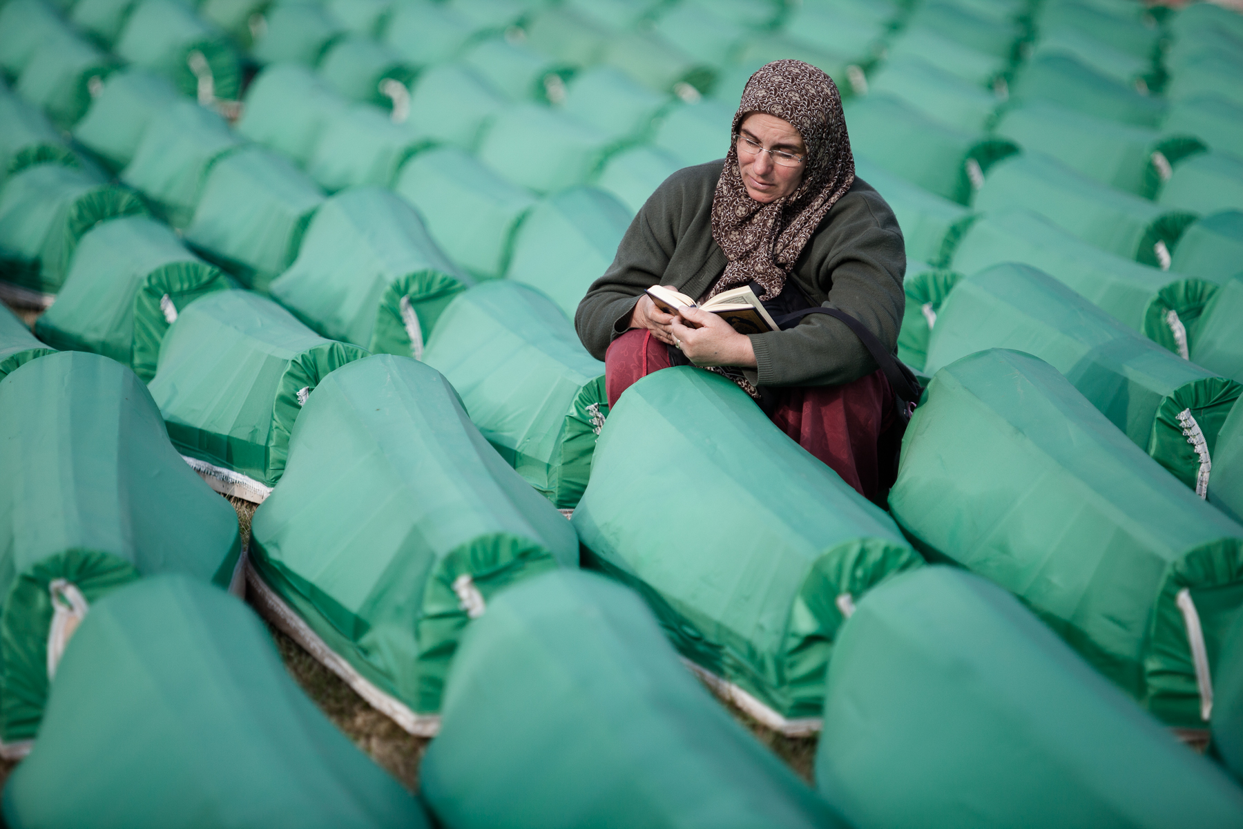 A woman prays among the rows of coffins at the Potocari cemetery in Srebrenica on July 11, 2010, before the memorial ceremony and mass burial of 775 newly identified victims of the 1995 Srebrenica massacre.