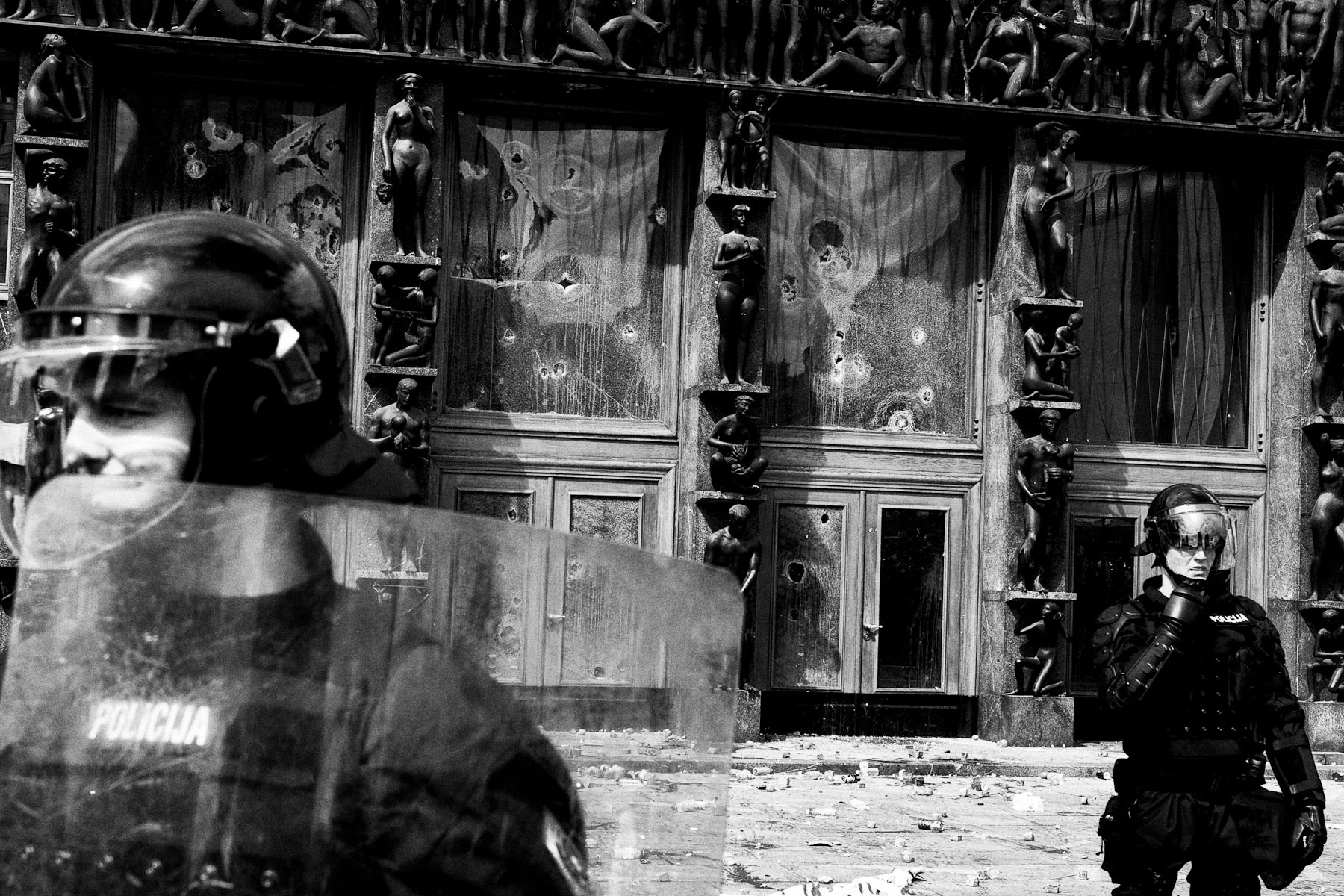 Riot police stand in front of a damaged entrance to the parliament building during anti-government student protests in Ljubljana, May 19, 2010.