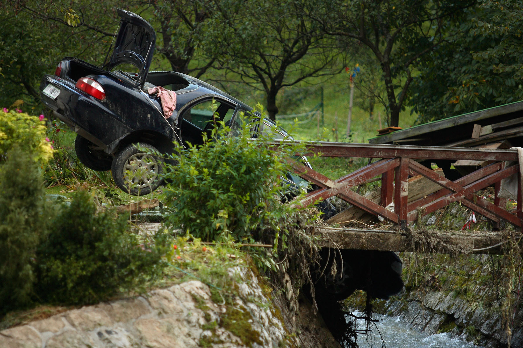 A car sits stranded on the bank of a smaller stream flowing into Sora river river that flooded Železniki the day before, picked the car up and dropped it there.