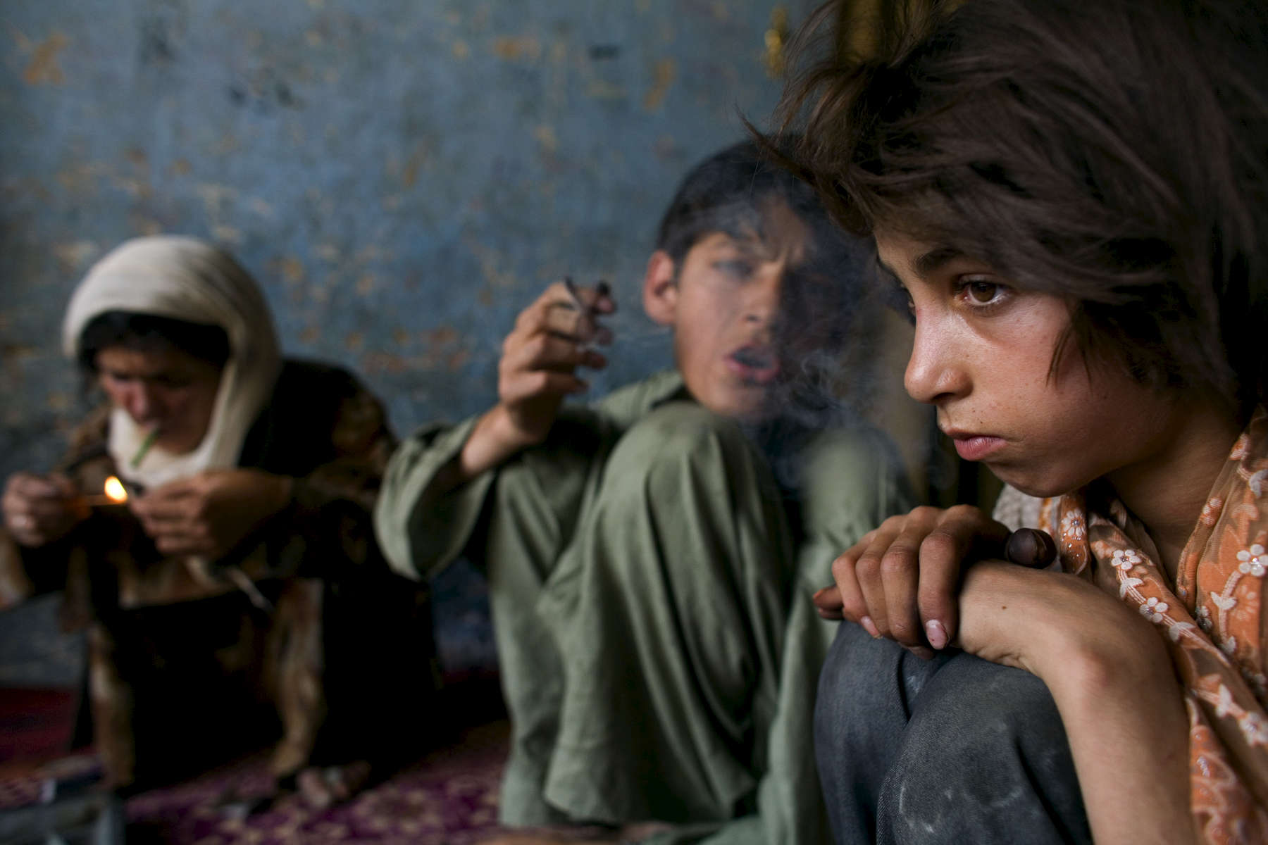Zaher, 14, smokes heroin along side his heroin addicted mother Sabera and her 11 year-old sister, Gulparai, at their home in Kabul.  The children began smoking after watching their widowed mother, a heroin addict for 4 years. August 27, 2007
