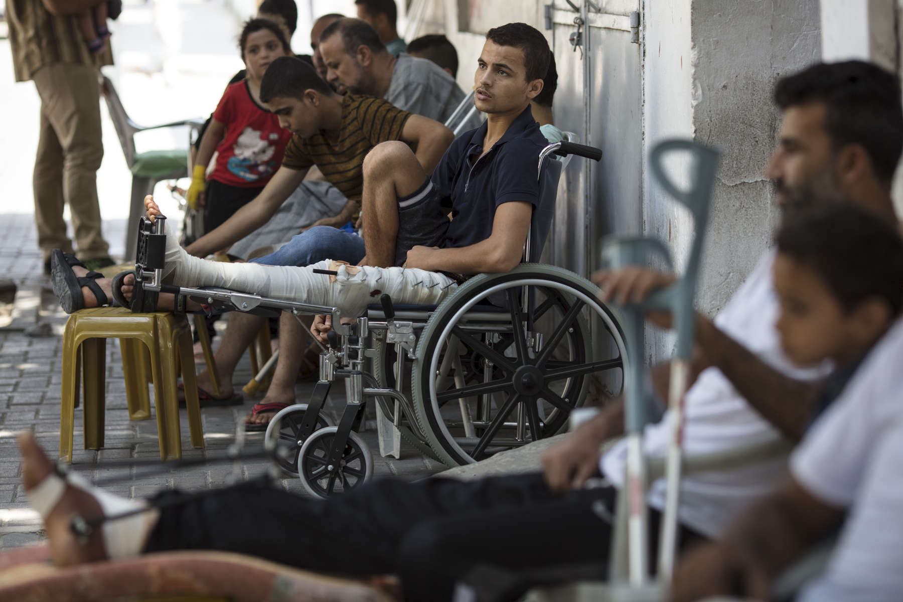 GAZA CITY, GAZA STRIP- MAY 20,2018: At the Médecins Sans Frontières (MSF) clinic male patients are lined up awaiting medical treatment on May 20,2018 in Gaza city, Gaza strip. MSF has focused their attention on treating injuries  caused by bullet wounds.According to the International Committee of the Red Cross (ICRC), 13,000 Palestinians were wounded (as of June 19, 2018), the majority severely, with some 1,400 struck by three to five bullets. No Israelis were physically harmed during this time period, Israel's use of deadly force was condemned during the UN general assembly on June 13 th along with other human rights organizations. The Israeli military (IDF) started using new weaponry, explosive bullets that shatter bones, tissue, destroying veins and arteries, the aim is to create a handicapped community, especially amongst the young male population. Many of the wounded protesters have to undergo multiple surgeries to try to save their limbs, and in some cases amputation is the only solution. With limited healthcare available in Gaza many were sent to Jordan and Turkey for further treatment. More issues that plague Gaza include a water supply that is 95 percent contaminated and a population forced to live without electricity for 21 hours a day. Gaza is compared to Venezuela with almost half of it’s labor force unemployed. Everyone is well aware that Gaza's two million inhabitants are trapped in a cycle of violence and poverty, living in an open air prison. The problems and complications affecting Gaza today are overwhelming. The world, seemingly accustomed to the suffering of the Gazan people turns a blind eye. (Photo by Paula Bronstein ) 