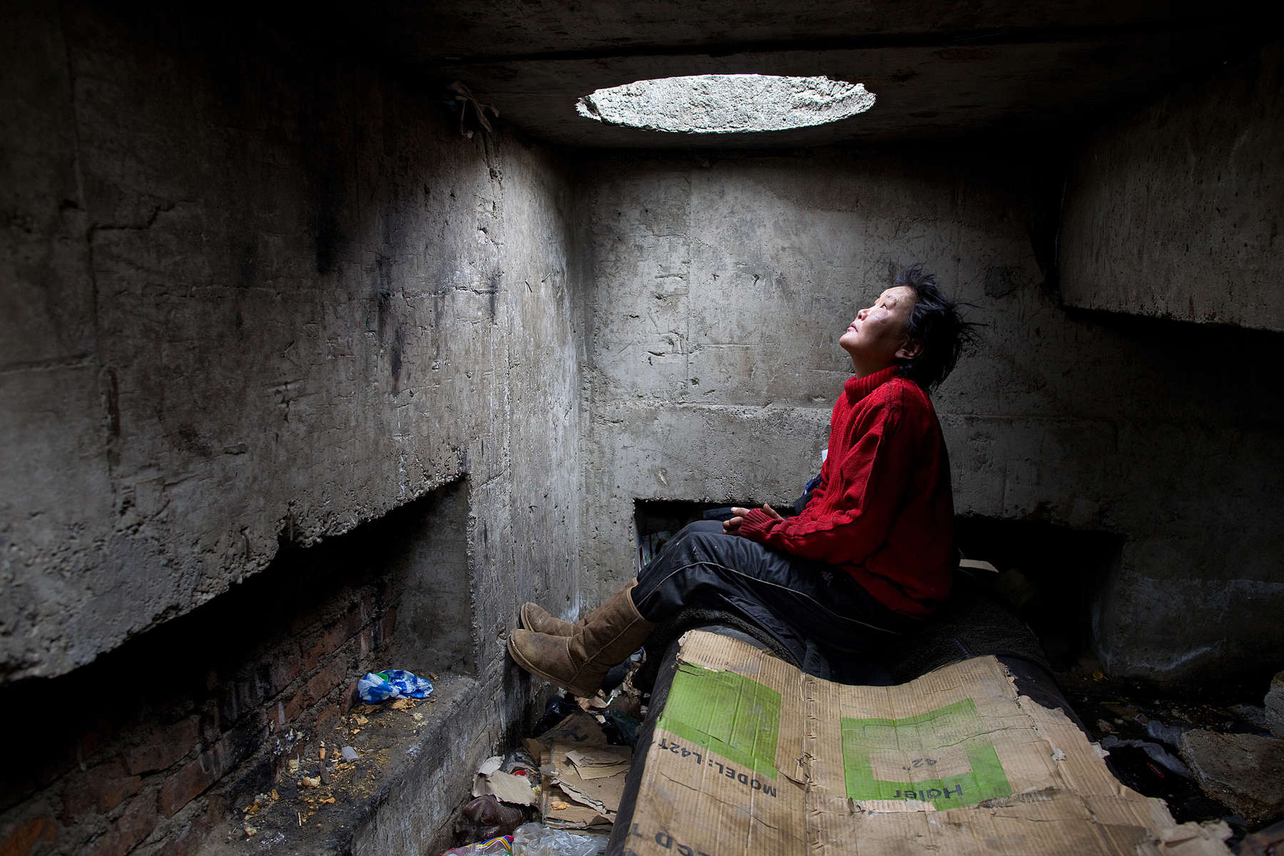ULAAN BAATAR, MONGOLIA-MARCH 13 : Erdenetsetseg,36,  sits on a water pipe inside the sewer filled with garbage where she lives  March13, 2010  in Ulaan Baatar, Mongolia. Erdenetsetseg moved to the capitol city from a province five years ago, without work she collects cans and bottles to make enough money to buy a little food and her daily fix of vodka. Since 70 years of communist rule ended in 1990, Mongolia has become one of the most pro-business countries. While economic reforms have brought prosperity to Ulaan Baatar, there still widespread unemployment, some used to work in the now defunct state industries. Approximately over 35% of Mongolians live below the poverty line, many unable to buy basic food needed to survive. Social problems include depression, alcohol abuse, domestic violence and crime. Mongolia suffers with a very high number of alcoholics, all consuming cheap Mongolian vodka that is readily available to the poor and the unemployed, Many Mongolians have immigrated to the capitol city from the far away provinces seeking employment.  For the homeless during the winter this means extreme hardship, for some homeless living in the sewers means warmth verses dealing with temperatures dropping as low as -25C mid- Winter. This year Mongolia has experienced the worst winter in 30 years. (Photo by Paula Bronstein /Getty Images)