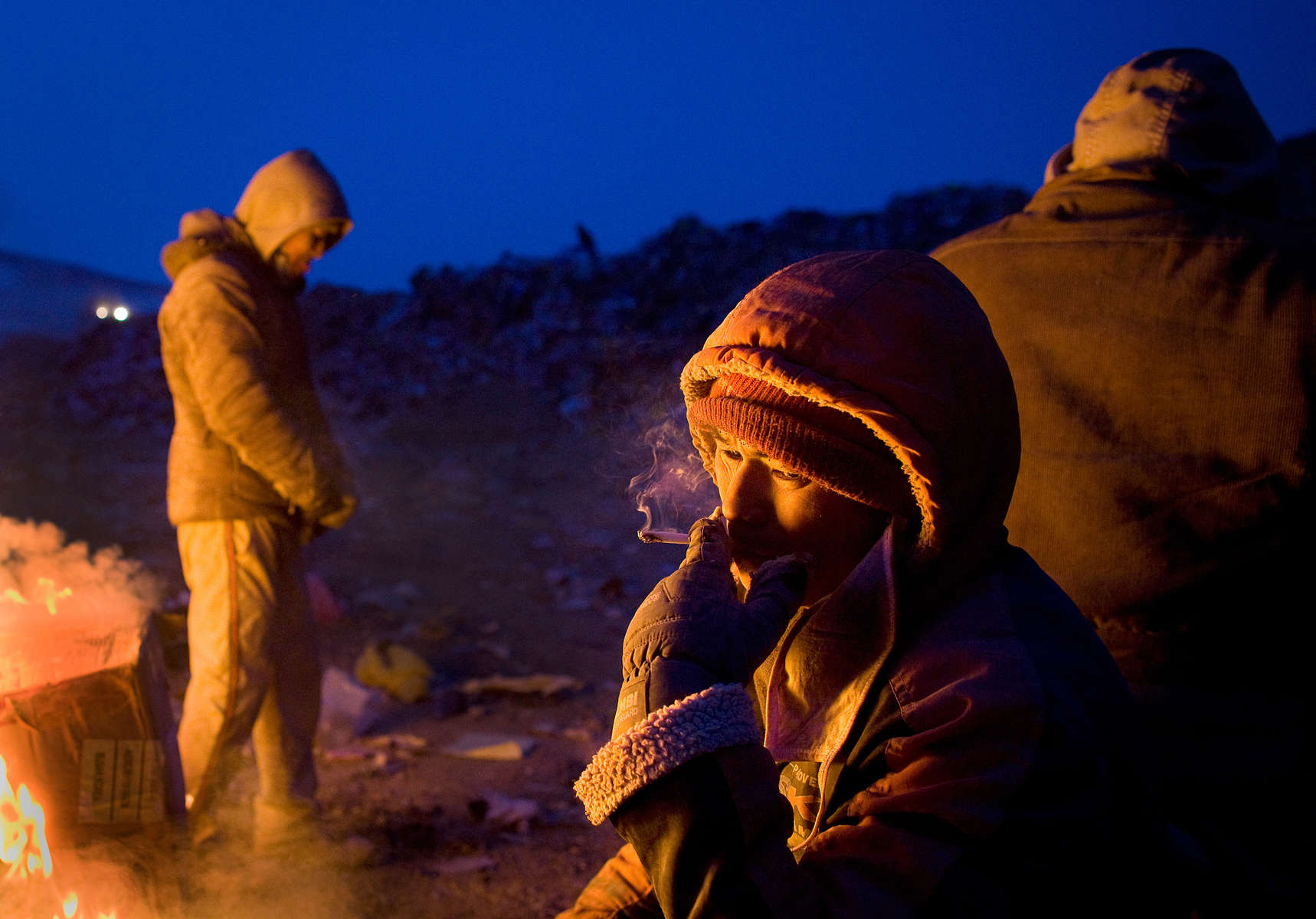ULAAN BAATAR, MONGOLIA-MARCH 5 : Mongolian men keep warm by a fire working collecting and recycling at a dump March 5, 2010  in Ulaan Baatar, Mongolia. The average money made per day is $6.50 US. Working at the garbage dump means extreme hardship, long hours outside in frigid temperatures dropping below -25C in the Winter as Mongolia experienced one of the worst Winters in 30 years. Presently the government has declared an emergency requiring foreign aid to alleviate the impact of the {quote} Zud{quote} ( Mongolian term for a multiple natural disaster) caused by bitter cold and thick snow. Currently 1.5 million goats,  921,000 sheep, 169,000 cows and yaks, 89,000 horses and 1,500 camels had died according to the various UN agency reports. Many Mongolians have immigrated to the capitol city from the far away provinces seeking employment, living in rented traditional circular felt yurts with no running water or electricity.(Photo by Paula Bronstein /Getty Images)
