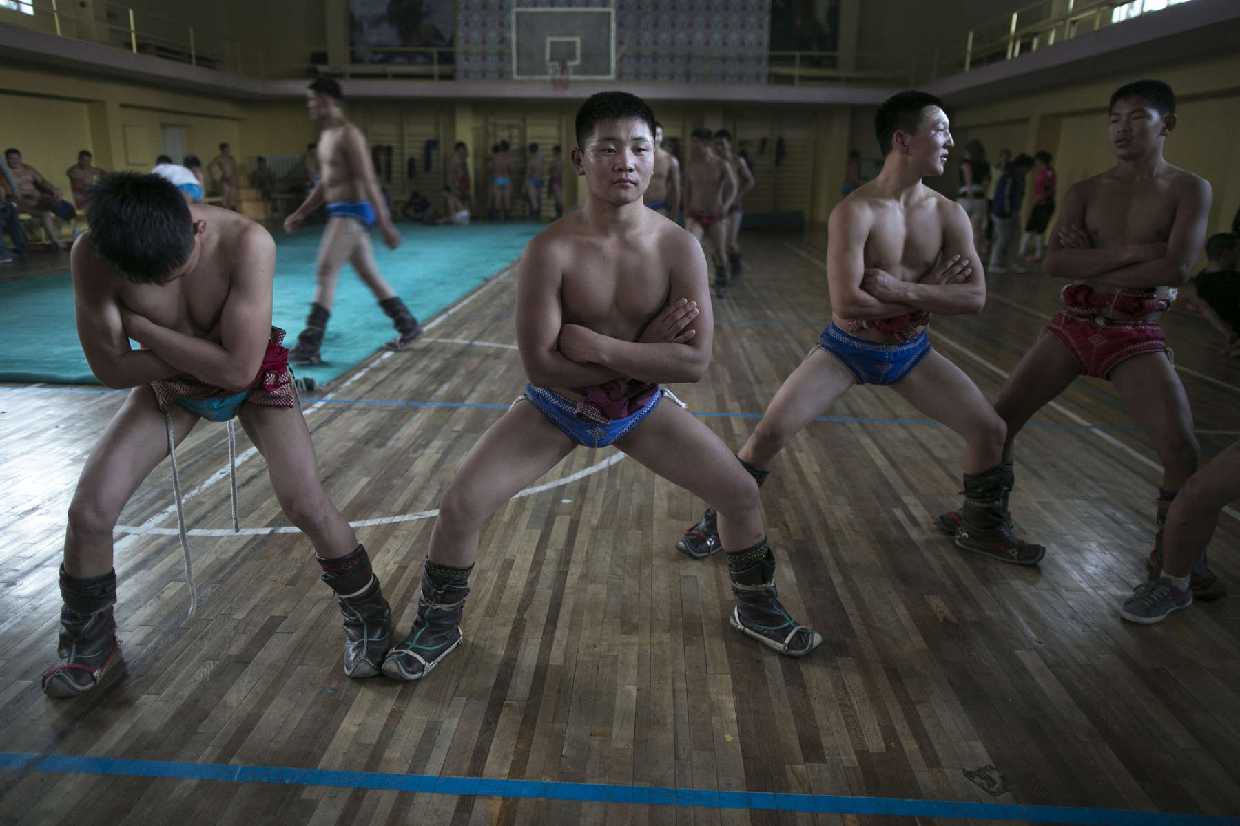Mongolian wrestlers practice their squats trying to strengthen their thighs during practice at a local wrestling school. Mongolia is the most sparsely populated country on earth, but its people are some of the strongest. In Mongolia, wrestling is the most important sport that runs deep into its culture along with horsemanship and archery. Going back for hundreds of years, history books tell the story of how Genghis Khan considered wrestling to be an important way to keep his army combat ready while back in the Qing Dynasty (1646–1911) regular wrestling events were held. In Mongolia’s capitol city, Ulan Batar is home to many wrestling schools where almost daily you can see dozens of young men sweating in crowded gyms while in schools both girls and boys are taught some wrestling techniques.While my photo story gives a real behind the scenes look, it is unusual for a woman to document this macho scene of sweat and endurance.