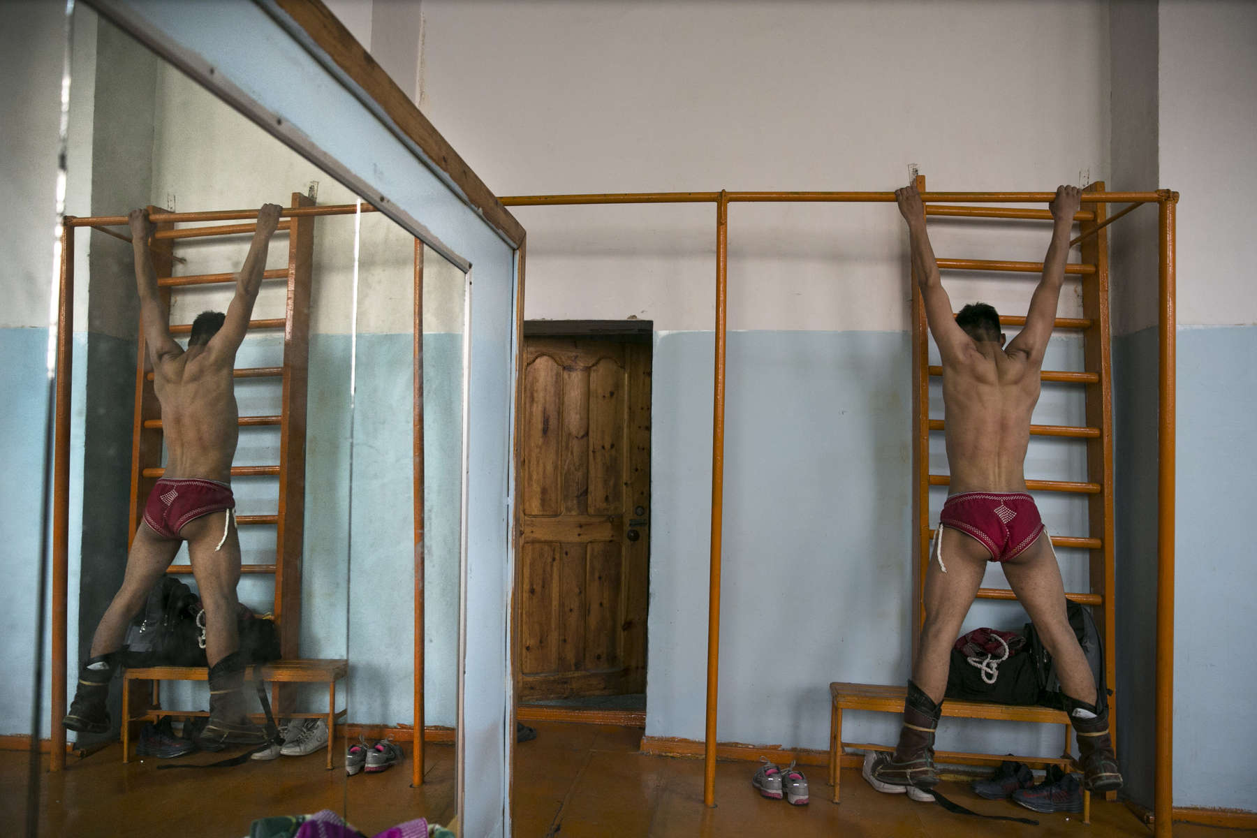 A Mongolian wrestler uses a bar to do pull ups during practice at a local wrestling schol. Mongolia is the most sparsely populated country on earth, but its people are some of the strongest. In Mongolia, wrestling is the most important sport that runs deep into its culture along with horsemanship and archery. Going back for hundreds of years, history books tell the story of how Genghis Khan considered wrestling to be an important way to keep his army combat ready while back in the Qing Dynasty (1646–1911) regular wrestling events were held. In Mongolia’s capitol city, Ulan Batar is home to many wrestling schools where almost daily you can see dozens of young men sweating in crowded gyms while in schools both girls and boys are taught some wrestling techniques.While my photo story gives a real behind the scenes look, it is unusual for a woman to document this macho scene of sweat and endurance.