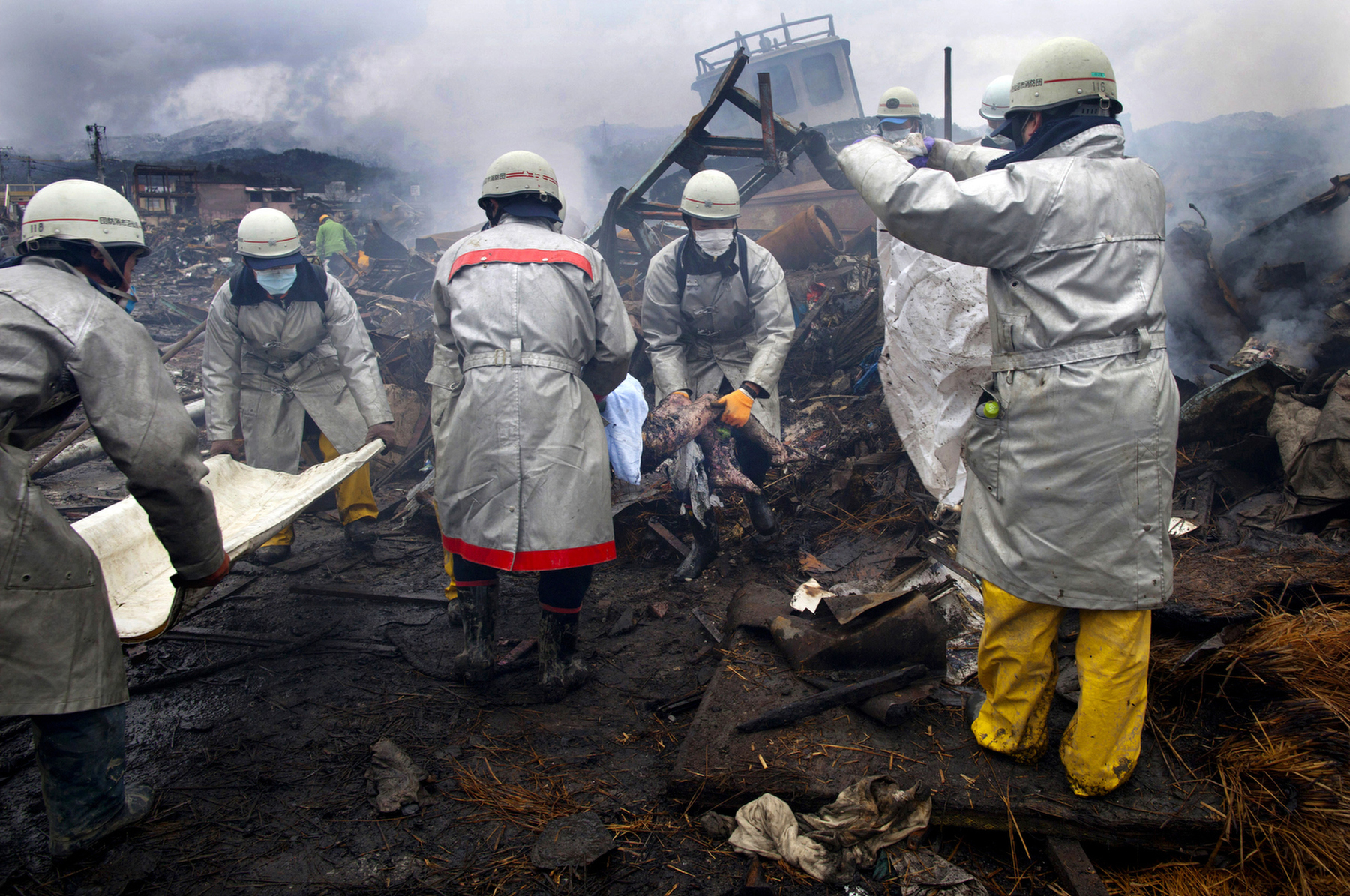 Rescue workers carry a charred body from the rubble of a village destroyed by the devastating earthquake, fires and tsunami March 16, 2011 in Kesennuma, Miyagi province, Japan.  One of the world\'s most developed country suffered it\'s worst natural disaster as a strong 8.9 earthquake followed by a Tsunami hit the north-central coast of Japan, killing thousands, followed by a potential nuclear meltdown after the country\'s major nuclear plant was seriously damaged from the quake. 