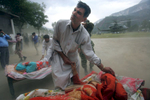MUZAFFARABAD, PAKISTAN-OCTOBER 11:  Earthquake victims wait to get emergency first aid in a makeshift trauma center as a helicopter blows dust and high winds where many survivors from  Muzaffarabad and neighboring villages where taken.(photo by Paula Bronstein for Time magazine /Getty Images)