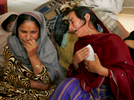 MUZAFFARABAD, PAKISTAN-OCTOBER 22:Naseem (L) and Nazmeen Akther (R) weep as they loook at photos of their children killed in the earthquake inside their tent in Muzaffarabad, Pakistan controlled Kashmir October 22,2005. the mothers joined relatives who visited them today to mourn their loss together. The current death toll is now believed to be over 50,000 from the South Asian earthquake that happened 2 weeks ago. Over 3 million people are without proper shelter and aid organizations including the U.N are warning that thousands could die in remote mountainous regions as Winter approaches. Atleast 1,400 died in Indian-Kashmir. (photo by Paula Bronstein /Getty Images)