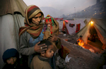 MUZAFFARABAD, PAKISTAN-DECEMBER 16: Nasim Jan holds her daughter Mehnaz, 2 months old with Farooq and Abdullah as try and keep warm residing at a tented camp in Muzaffarabad, December 16, 2005. The camp has over 700 tents housing 3,336 earthquake victims who have moved from various area villages for the winter months.  Lack of snow is giving the quake survivors a break but they are still struggling in over crowded tented camps while fighting the cold weather with a lack of shelter.  (photo by Paula Bronstein /Getty Images)
