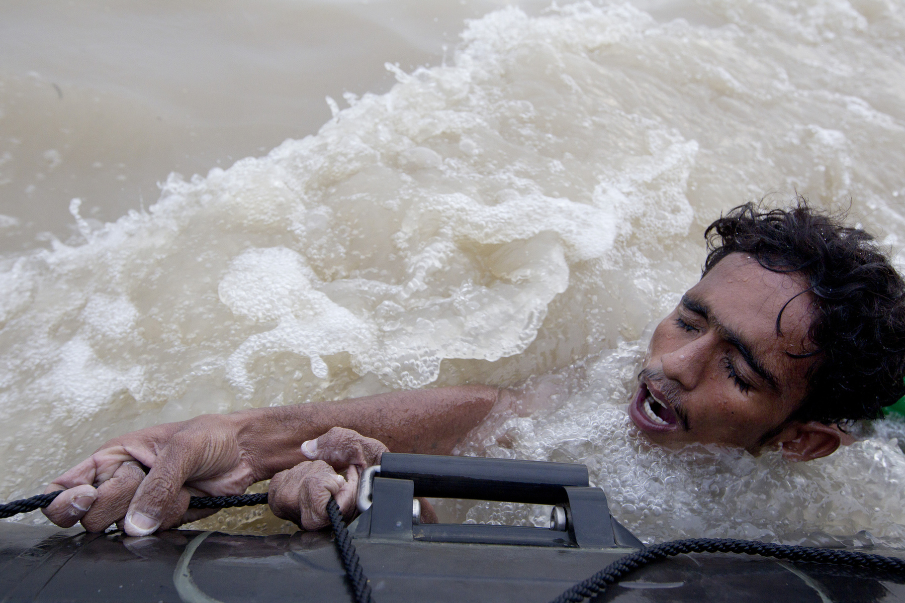 SUKKUR, PAKISTAN-AUG 10 : A Pakistan man holds on with all his strength as flood victims get evacuated by the Pakistan Navy on a boat rescue mission as flood waters continue at a very high level August 10, 2010 in Sukkur, Pakistan. Pakistan is suffering from the worst flooding in 80 years as the army and aid organizations struggle to cope with the scope of the wide spread disaster which has killed atleast 1,500 people and displaced millions. In addition, Pakistani\'s have become more frustrated with the government\'s repsonse along with President Asif Ali Zardari trip to Europe as Islamic charities step up to gain local grass roots support as they did in the 2005 earthquake.(Photo by Paula Bronstein/ Getty Images)WASHED AWAY_PAKISTAN FLOODS