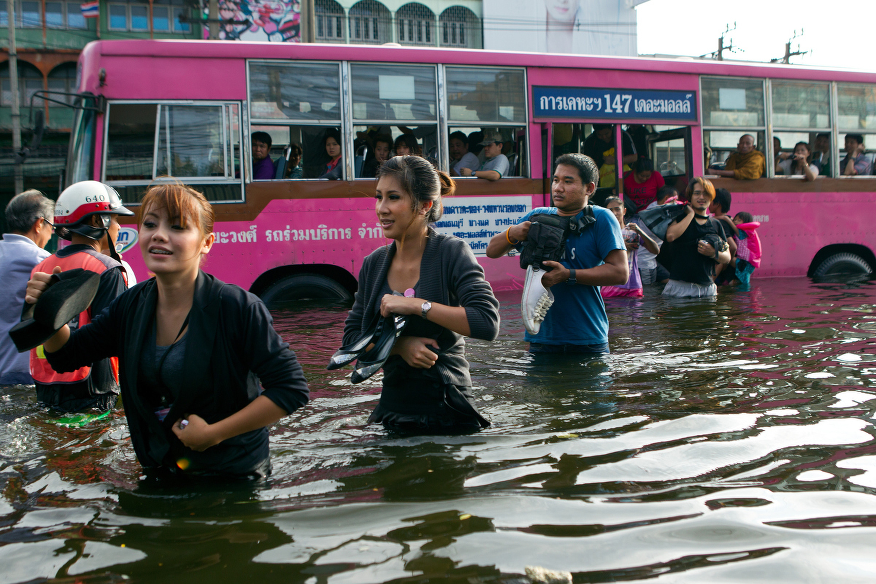 BANGKOK,THAILAND - NOVEMBER 7 :  Commuters get off a city bus into waist deep water in the Bang Kae district southwest of the capitol city November 7, 2011 in Bangkok, Thailand. Over seven major industrial parks in Bangkok and, thousands of factories have been closed in the central Thai province of Ayutthaya and Nonthaburi with millions of tons of rice damaged. Across the country, the flooding which is now in its third month has affected 25 of Thailand\'s 64 provinces. Thailand is experiencing the worst flooding in over 50 years which has affected more than nine million people. Over 400 people have died in flood-related incidents since late July according to the Department of Disaster Prevention and Mitigation.(Photo by Paula Bronstein /Getty Images)