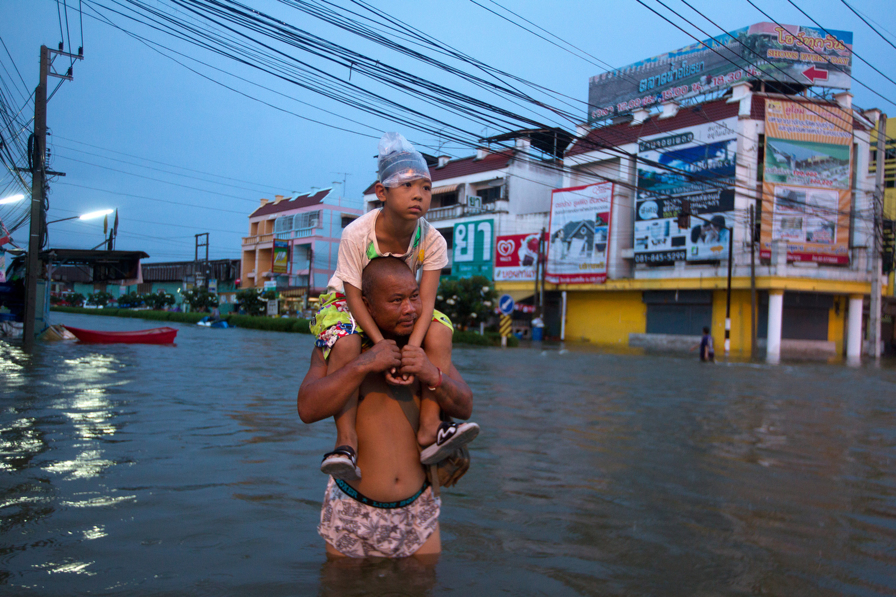 AYUTTHAYA,THAILAND - OCTOBER 10TH:  A Thai man holds his daughter a he wades through the flooded streets October 10, 2011 in Ayutthaya, Thailand Around 200 factories closed in the central Thai province of Ayutthaya because of flooding, which is posing a threat to Bangkok as well. Over 260 people have died in flood-related incidents since late July according to the Department of Disaster Prevention and Mitigation. Some areas of the country are experiencing the worst flooding in 50 years, mainly in the centre, north and northeast.(Photo by Paula Bronstein /Getty Images)