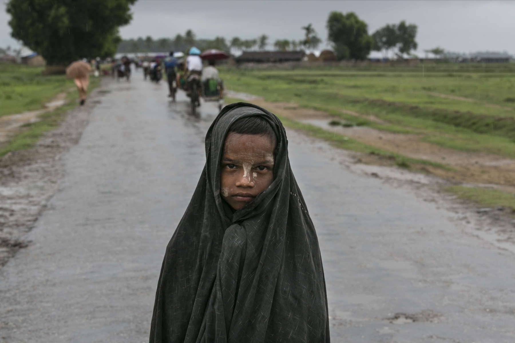 A boy covers himself from the rain as he waits for medical care outside the makeshift Aung Clinic which serves many Rohingya with a few dedicated staff giving free medical care. ( Photo by Paula Bronstein/ For The Washington Post )
