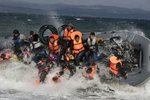 LESBOS, GREECE - OCTOBER 31: Refugees arriving to the island of Lesbos fall out of a boat as it capsizes landing in rough seas coming from Turkey on October 31, 2015 in Lesbos, Greece. Dozens of rafts and boats are still making the journey daily via the Aegean Sea, over 590,000 people have crossed into the gateway of Europe. Nearly all of those are from the war zones of Syria, Iraq and Afghanistan. (Photo by Paula Bronstein)