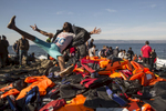 LESBOS, GREECE - OCTOBER 27: A Syrian refugee jumps for joy onto a pile of life jackets after arriving on an overcrowded raft to the island of Lesbos, Greece on October 27, 2015. Dozens of rafts and boats are still making the journey daily via the Aegean Sea, over 590,000 people have crossed into the gateway of Europe. Nearly all of those are from the war zones of Syria, Iraq and Afghanistan. (Photo by Paula Bronstein)