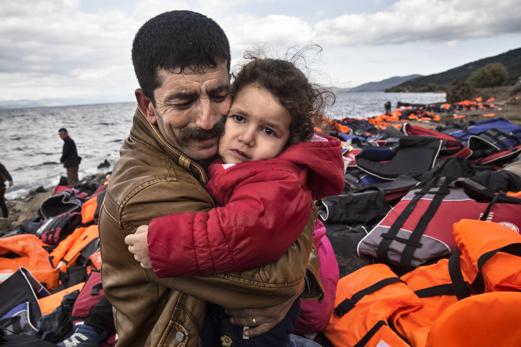 LESBOS, GREECE - OCTOBER 25: An Iraqi refugee cries as he holds his daughter after arriving safely to Lesbos from Turkey. Colder weather and rough seas continue to cause deaths at sea as thousands travel in overcrowded small rafts. According to the IOM, an estimated 100,000 people landed in Greece, an average of almost 4,500 per day in late October and November. Nearly all of those entering Greece on a boat from Turkey are from the war zones of Syria, Iraq and Afghanistan. (Photo by Paula Bronstein)
