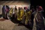 LESBOS, GREECE - OCTOBER 25: Women keep warm wrapped in emergency blankets while standing in line to change out of their wet clothes at a transitional camp. Colder weather and rough seas continue to cause deaths at sea as thousands travel in overcrowded small rafts. According to the IOM, an estimated 100,000 people landed in Greece, an average of almost 4,500 per day in late October and November. Nearly all of those entering Greece on a boat from Turkey are from the war zones of Syria, Iraq and Afghanistan. (Photo by Paula Bronstein)