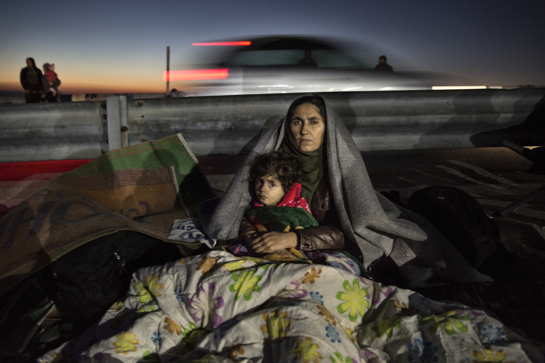 LESBOS, GREECE - NOVEMBER 4: An Iraqi mother sits with her daughter at the Oxy transitional camp for another night sleeping in the cold. Colder weather and rough seas continue to cause deaths at sea as thousands travel in overcrowded small rafts. According to the IOM, an estimated 100,000 people landed in Greece, an average of almost 4,500 per day in late October and November. Nearly all of those entering Greece on a boat from Turkey are from the war zones of Syria, Iraq and Afghanistan. (Photo by Paula Bronstein)
