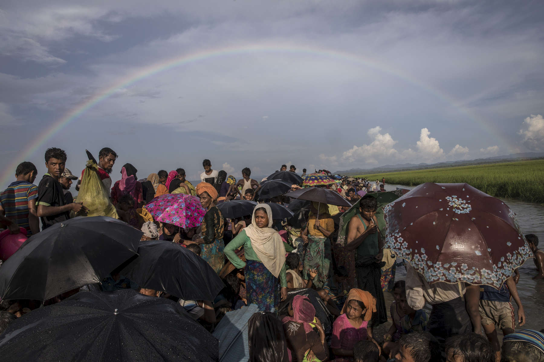 PALONG KHALI, BANGLADESH - OCTOBER 16: Thousands of Rohingya refugees fleeing from Myanmar are  kept under a tight security by Bangladeshi military after crossing the border in a rice patty field near Palang Khali, Cox's Bazar, Bangladesh. A rainbow appeared after a brief rainstorm. Well over a half a million Rohingya refugees have fled into Bangladesh since late August during the outbreak of violence in Rakhine state causing a humanitarian crisis in the region with continued challenges for aid agencies. (Photo by Paula Bronstein/Getty Images)