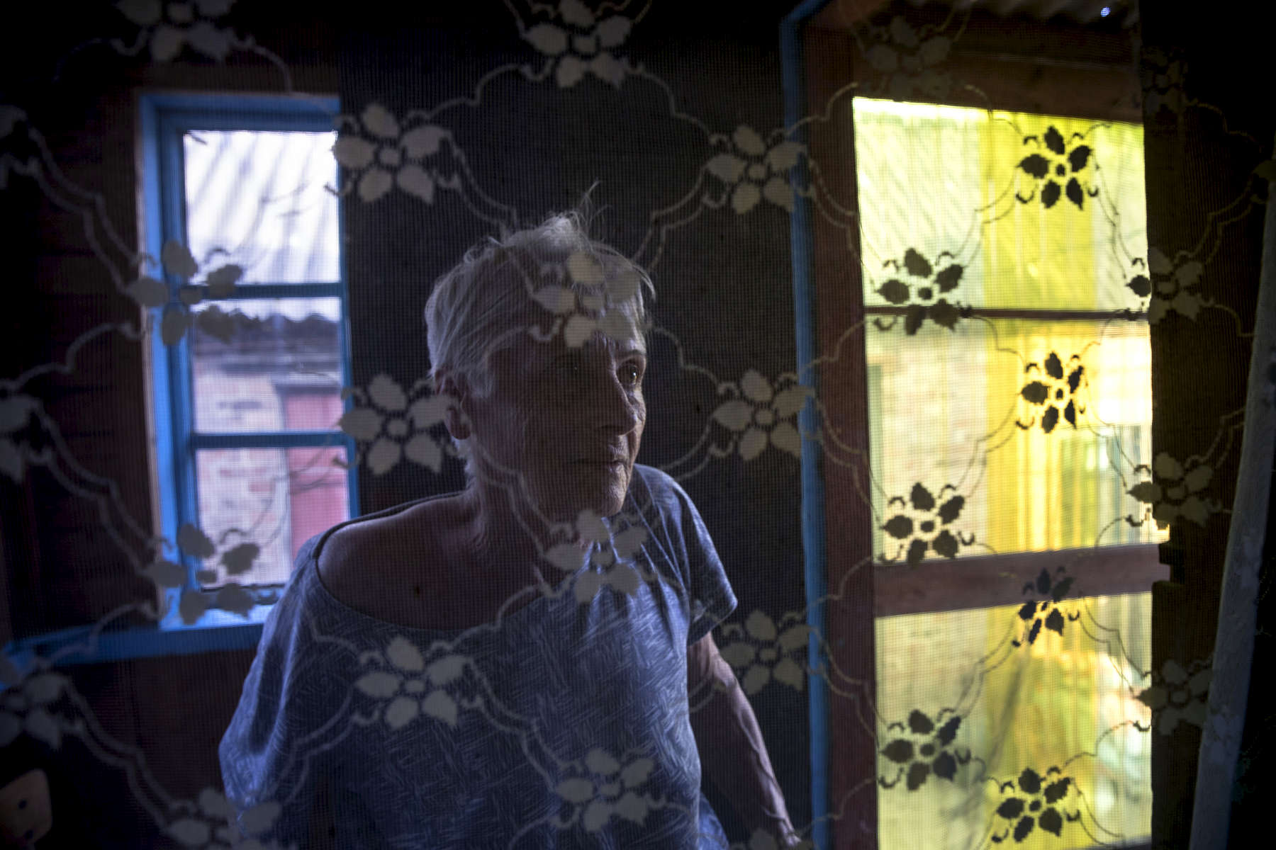 Chasov Yar, Donetsk region: Lyudmila Yevgenievna, age 64  from Chasov Yar is seen by windows at All her relatives have died and she was left alone and couldn't take care of the household and herself. The owner of the nursing home brings her to the church by car every Sunday and she stays for 3-hour service.Evgeniy Tkachev has founded the elderly care facility with his own money. He bought two private houses across the street from each other. One house is for elderly women, another for men. {quote}I evacuate elderly people from the stress affect by the conflict.{quote}These people have nowhere to go. They have relatives who do not care about them. They can not stay at the state-run nursing home either{quote}. 50% of the elderly here do not receive their pensions due to the loss of the documents.