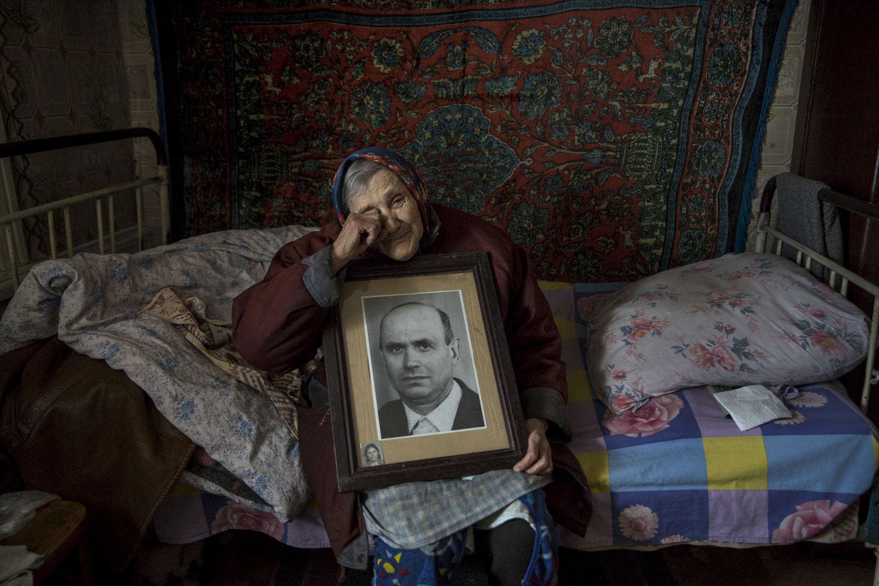 Katerinovka, Lugansk: Natalia Reshetnyakova, age 83 holds a portrait of her late husband who she was married to for over 50 years. She lives alone now. The only thing left reminding her of her husband is this portrait. The population of Natalia's village comprises less than 300 people. The village is exposed to the sniper’s fire as the contact line is just few kilometers away.