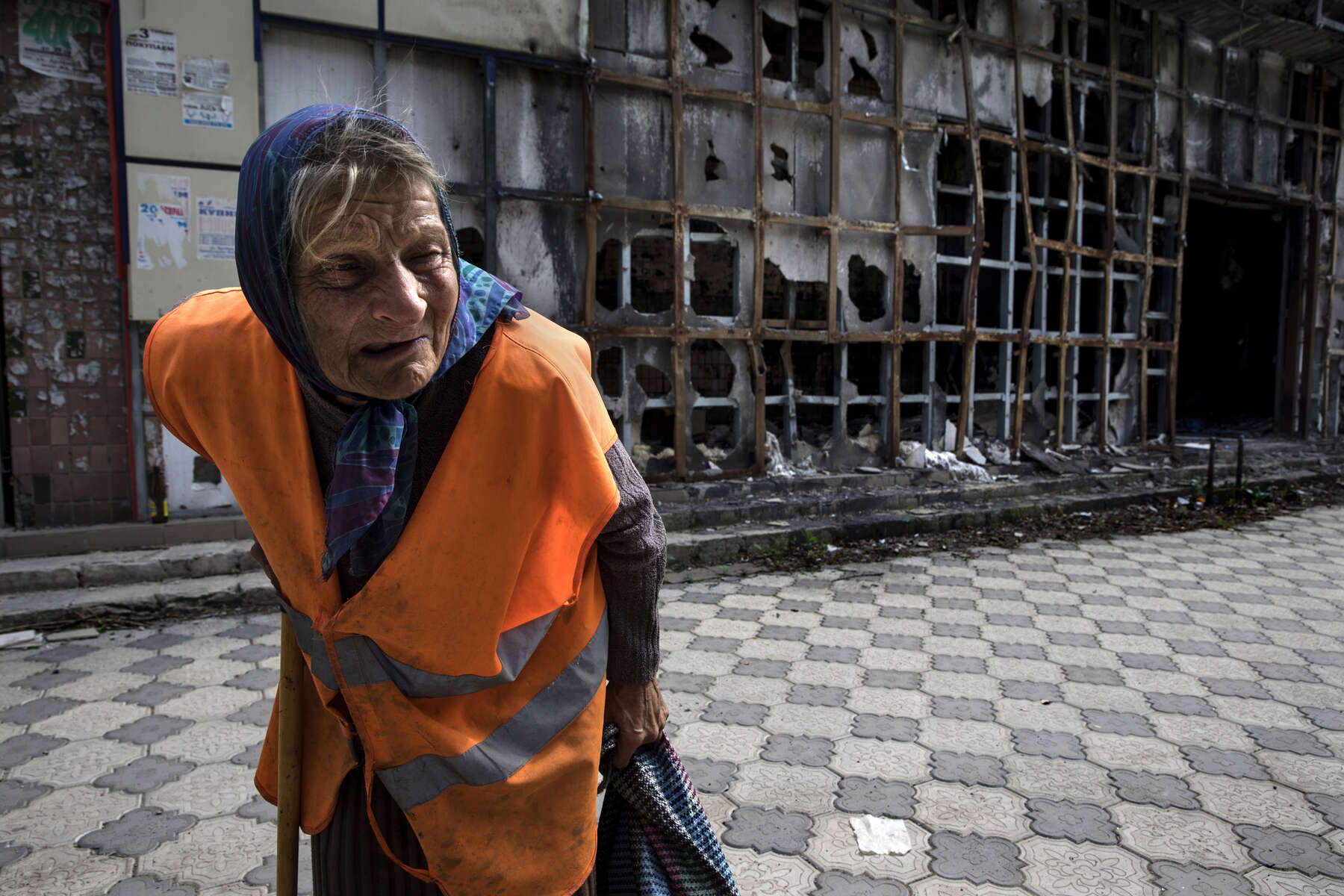 Donetsk People's Republic:Raisa Andreyevna, 72, walks by a local market area which was destroyed back in 2015. Since the start of the war she can no longer receive her Ukrainian pension of $50 a month so works as a janitor which pays her enough to survive. Originally from Russia, she now lives alone. Her children and grandchildren have all moved away to safer areas as part of Donetsk remain dangerous and occasionally gets shelled. {quote}I am not afraid to get killed because I have already lived my life but they have children they have to take care of. 