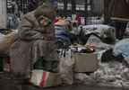  Donetsk, People's Republic (DPR) : Galina Mikhailovna , age 79, waits for customers at a second hand market in suffering during a cold winter day in February. She sells used goods that others give to her in the market for pensioners, sits in the snow with some street dogs. She has no pension, she never went to Ukraine to register, claims she can‚Äôt afford to travel to the other side every 57 days which is required by the government. She is in  debt so can’t afford to pay for heat and water in her apartment anymore. 