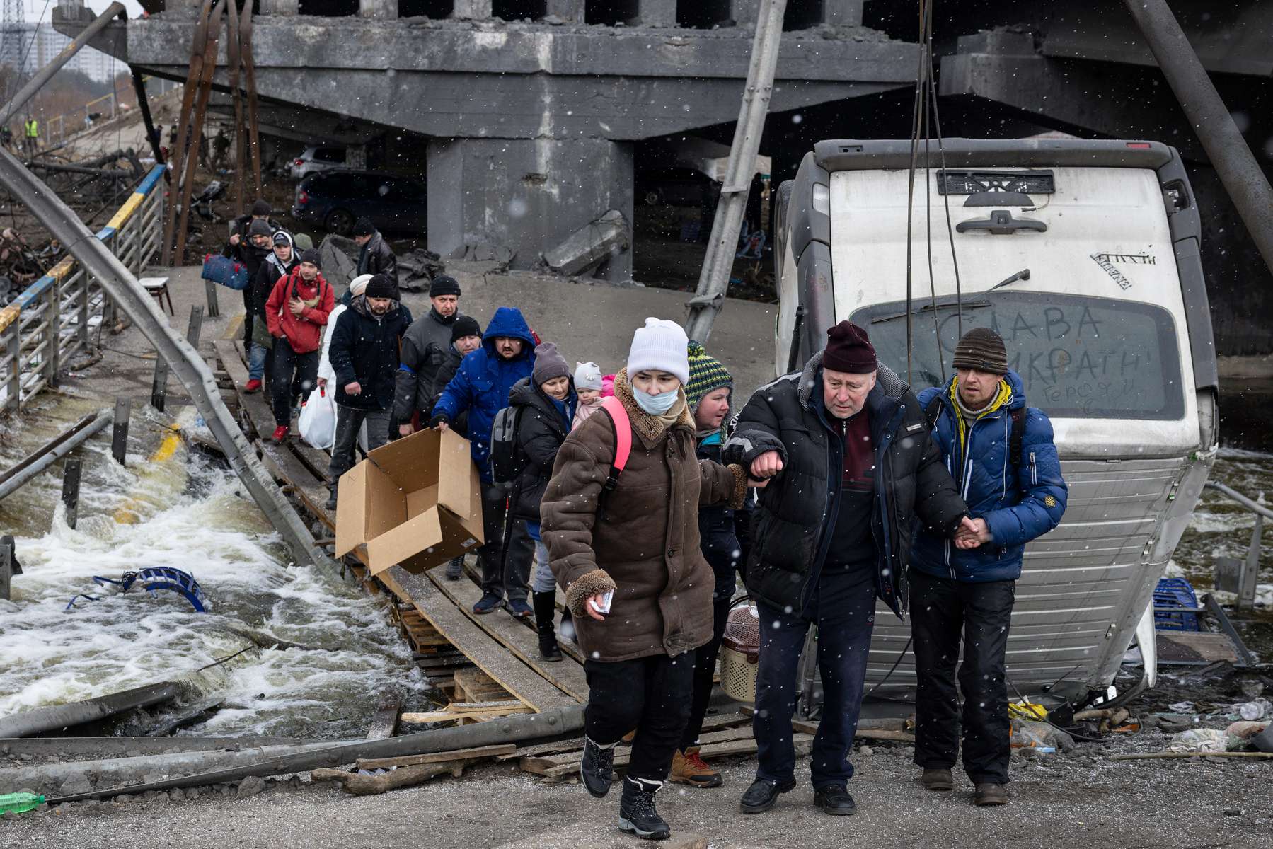 Residents of Irpin make their way over a destroyed bridge on March 13, 2022 as Russians continue their military incursion of the Kyiv suburb. 
