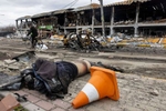  A man rides his bicycle past a destroyed shopping center as a dead body lays on the road in Bucha on April 6, 2022.