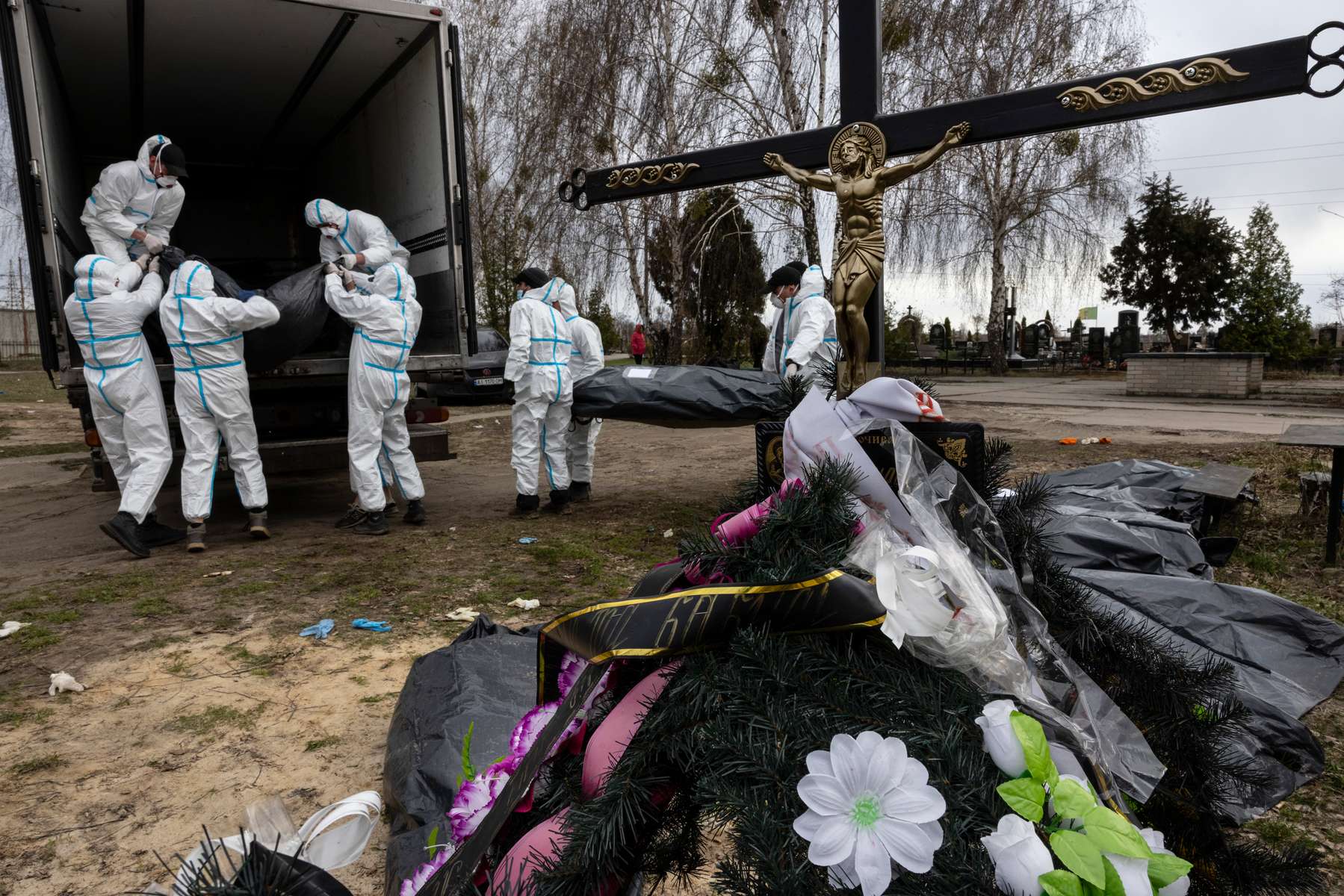 BUCHA : Workers in protective suits take dozens of bodies to the morgue from the Bucha cemetery for forensic examination and eventual burial on April 12, 2022.