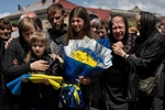 Funeral in Lviv of soldier Yuri Bohdnanovich Guk, age 41, his daughter, 8, holds the flag as her mother Katerina hugs her. He was killed on May 9 in the Donetsk district. He was a solider with the 68th brigade.