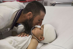 KABUL, AFGHANISTAN -MARCH 12, 2016:  Abdul Kabir kisses his son Noor Ahmad, 8, who is unconscious with a severe brain injury from an improvised explosive device (shell injury) from Mazar-E-Sharif Kabul on March 12, 2016. His father was also injured but recovered.As of April, 2016 the Emergency hospital stated that in the first quarter their patient numbers were up more than 30% from last year. They stated that patients are coming from much further distances now especially since the bombing of the MSF hospital in Kunduz last year which cared for many in the region.  Afghan civilians are at greater risk today than at any time since Taliban rule. According to UN statistics, in the first half of 2016 at least 1,600 people had died, and more than 3,500 people were injured, a 4 per cent increase in overall civilian causalities compared to the same period last year. The upsurge in violence has had devastating consequences for civilians, with suicide bombings and targeted attacks by the Taliban and other insurgents causing 70 percent of all civilian casualties.  