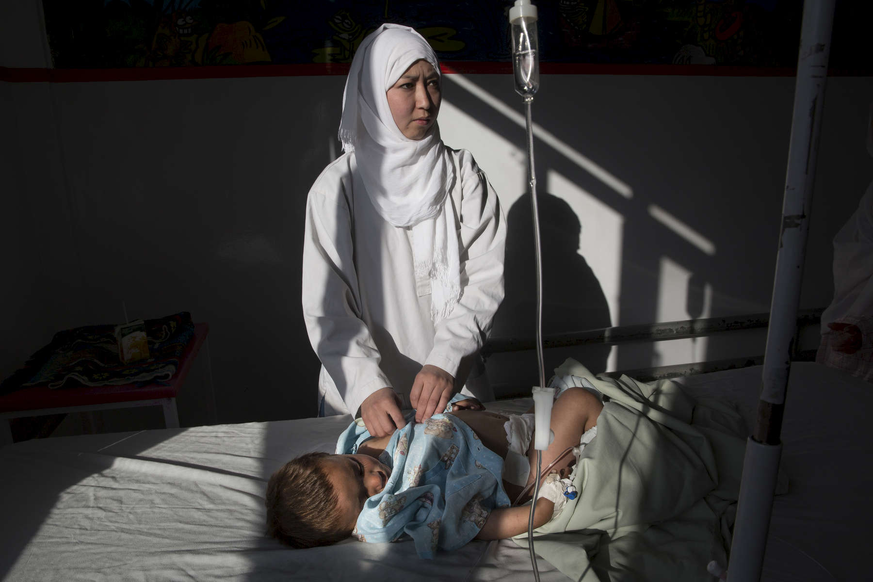 KABUL, AFGHANISTAN -MARCH 21, 2016:  Karima Mehrabi, a pediatric nurse cares for an infant in the women and children's ward at the Emergency hospital in Kabul on March 21, 2016. As of April, 2016 the Emergency hospital stated that in the first quarter their patient numbers were up more than 30% from last year. They stated that patients are coming from much further distances now especially since the bombing of the MSF hospital in Kunduz last year which cared for many in the region. Every year the UN comes out with their report documenting the unfortunate carnage from America’s longest and most costly war in history. Along with the price tag estimated in the hundreds of billions, the human toll from a 2015 UN Assistance Mission To Afghanistan (UNAMA) report stated the number of Afghan civilians killed and wounded surpassed 11,000.  which was the deadliest on record for civilians in Afghanistan since the US-led invasion more than 14 years ago. 