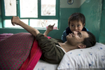 KABUL, AFGHANISTAN -MARCH 22, 2016:  Khuja Fareed, 24, a quadriplegic enjoys some time with his niece Roksar, 3 and a half years,  at his home in Kabul on March 22, 2016. He is now a quadrapalegic injured while delivering supplies to a military base truck driver for the US military until he was shot in the neck during fighting between the Taliban and the US military. With no financial help from the US military or the Afghan government Khuja depends on his family to care for him.Every year the UN comes out with their report documenting the unfortunate carnage from America’s longest and most costly war in history. Along with the price tag estimated in the hundreds of billions, the human toll from a 2015 UN Assistance Mission To Afghanistan (UNAMA) report stated the number of Afghan civilians killed and wounded surpassed 11,000.  which was the deadliest on record for civilians in Afghanistan since the US-led invasion more than 14 years ago. 
